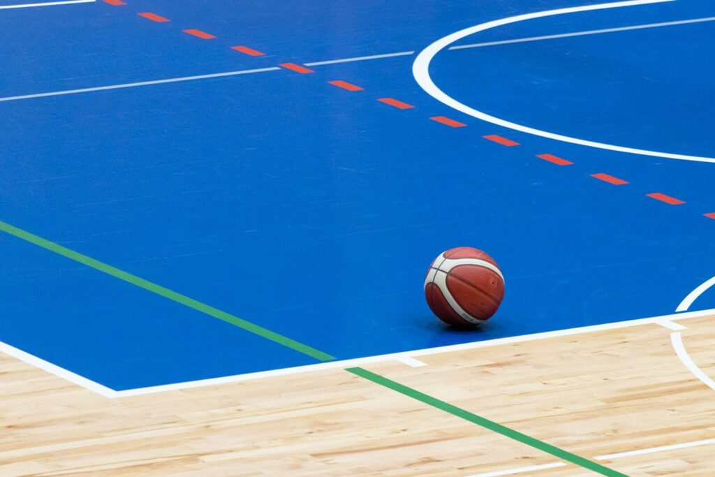 A basketball rests on a blue court
